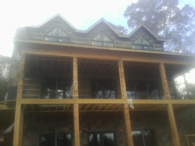 Dormers and porch framing on a large log home under construction — Roof Coating work by our crew in Two Dot