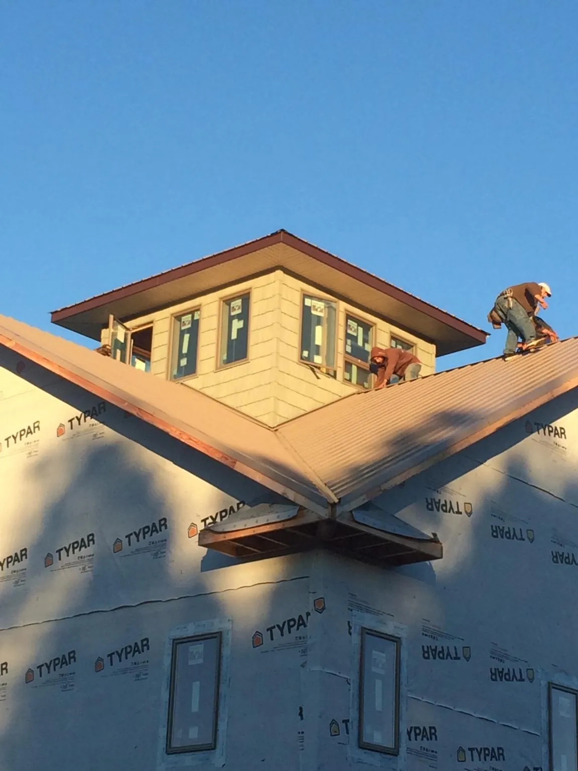 Roofers working around a rooftop cupola on a new metal roof at sunset — Roof Waterproofing in Two Dot by Roofing Brothers